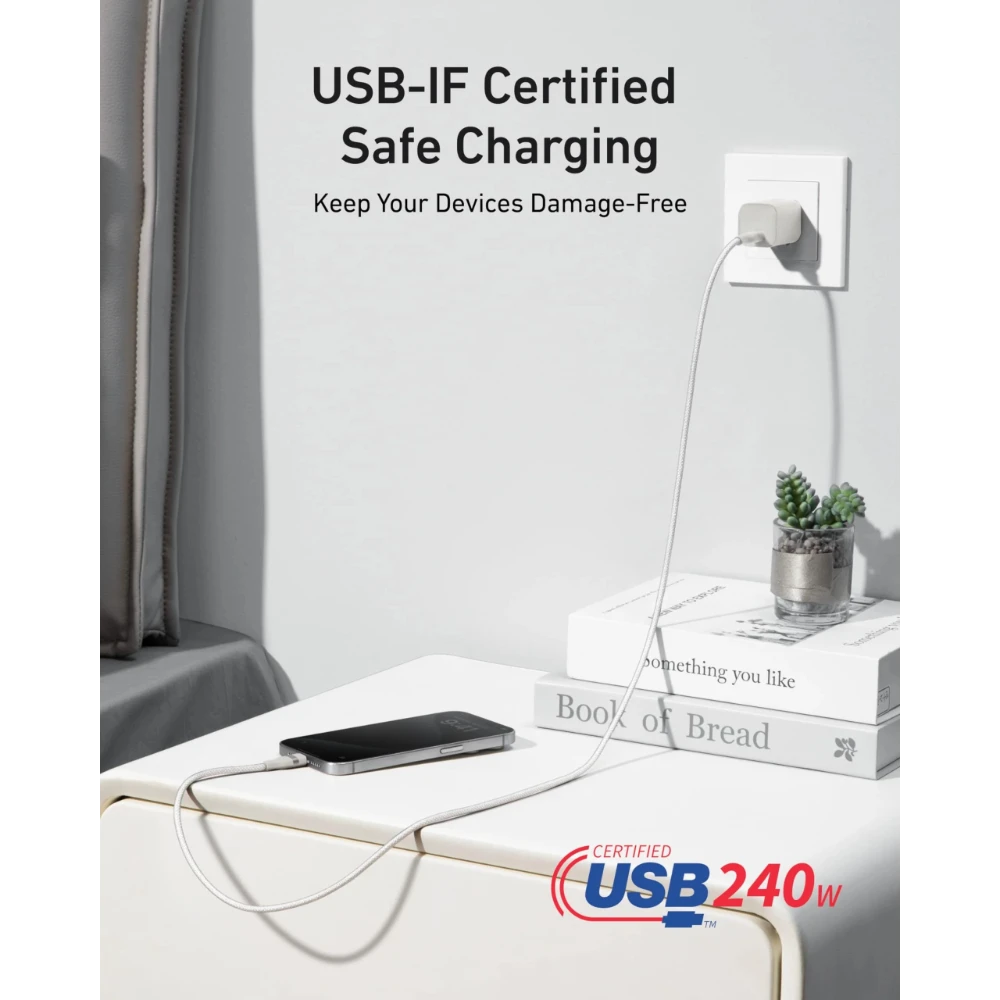 White Anker USB-C to USB-C 240W charging cable plugged into wall and connected to phone on table.