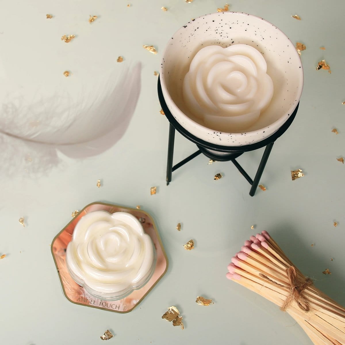 Fragrance Wax Melt Angels Touch shaped like a white rose with a burner and a bundle of matches on a light surface with gold
