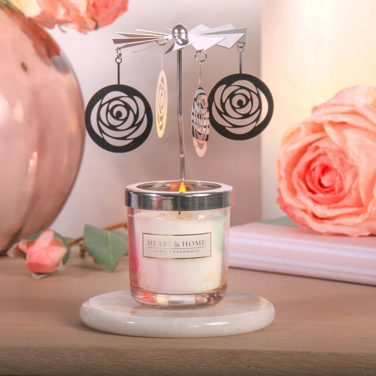 Heart & Home fragrance mini candle with rotating metal carousel featuring hanging rose cutouts on marble base