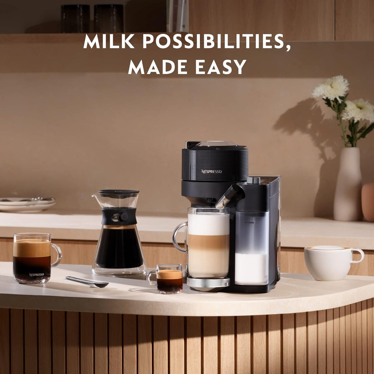 Delonghi Nespresso Vertuo Lattissima in black with milk frother, coffee cups, and carafe on kitchen counter.