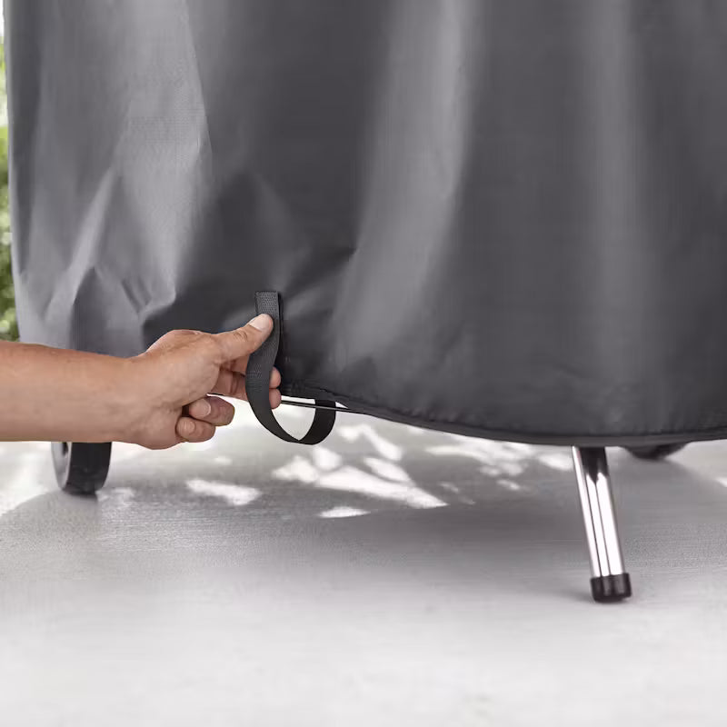 Hand pulling strap on the bottom edge of a black Weber Premium Barbecue 57cm Master Touch Cover