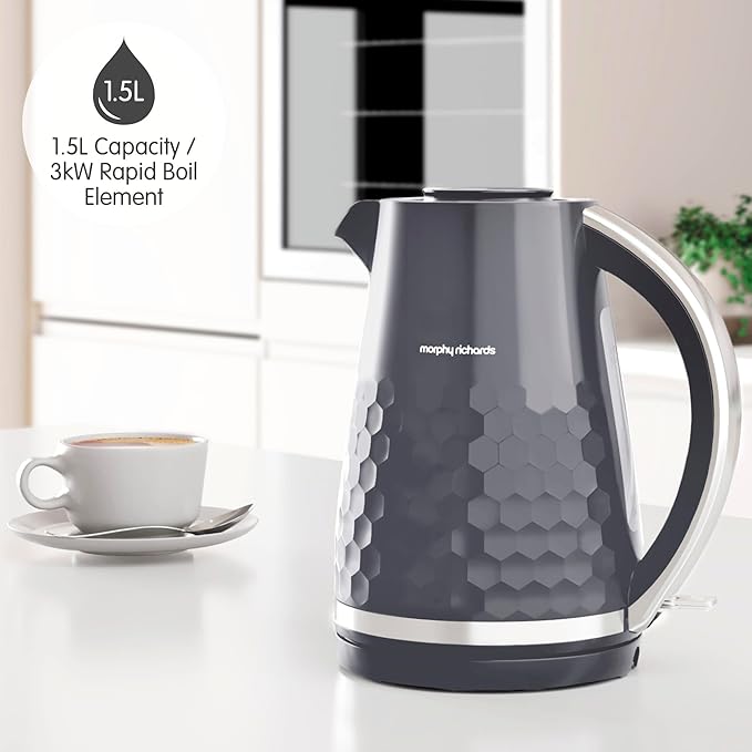 Grey Morphy Richards Hive Kettle with honeycomb texture and curved handle on a white kitchen counter next to a cup of coffee