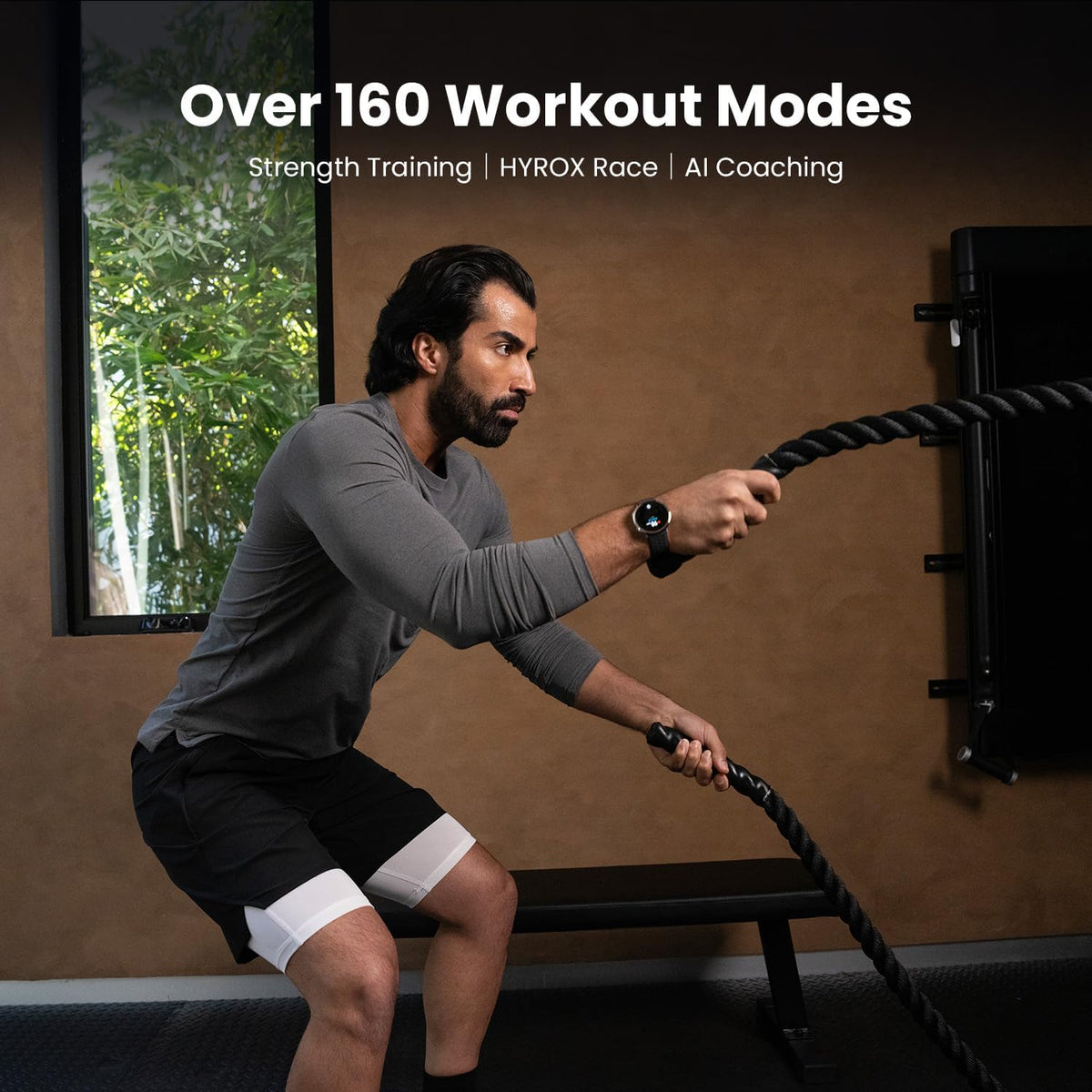 Man in gray shirt using battle ropes wearing Amazfit Active 2 black sport silicone smartwatch