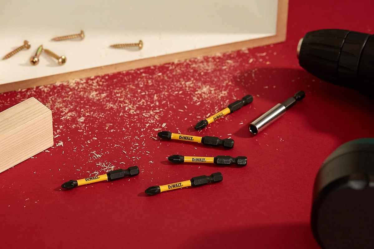 Five DeWalt Extreme Impact Torsion PZ2 x 50mm bits on a red surface with wood shavings and drill parts.