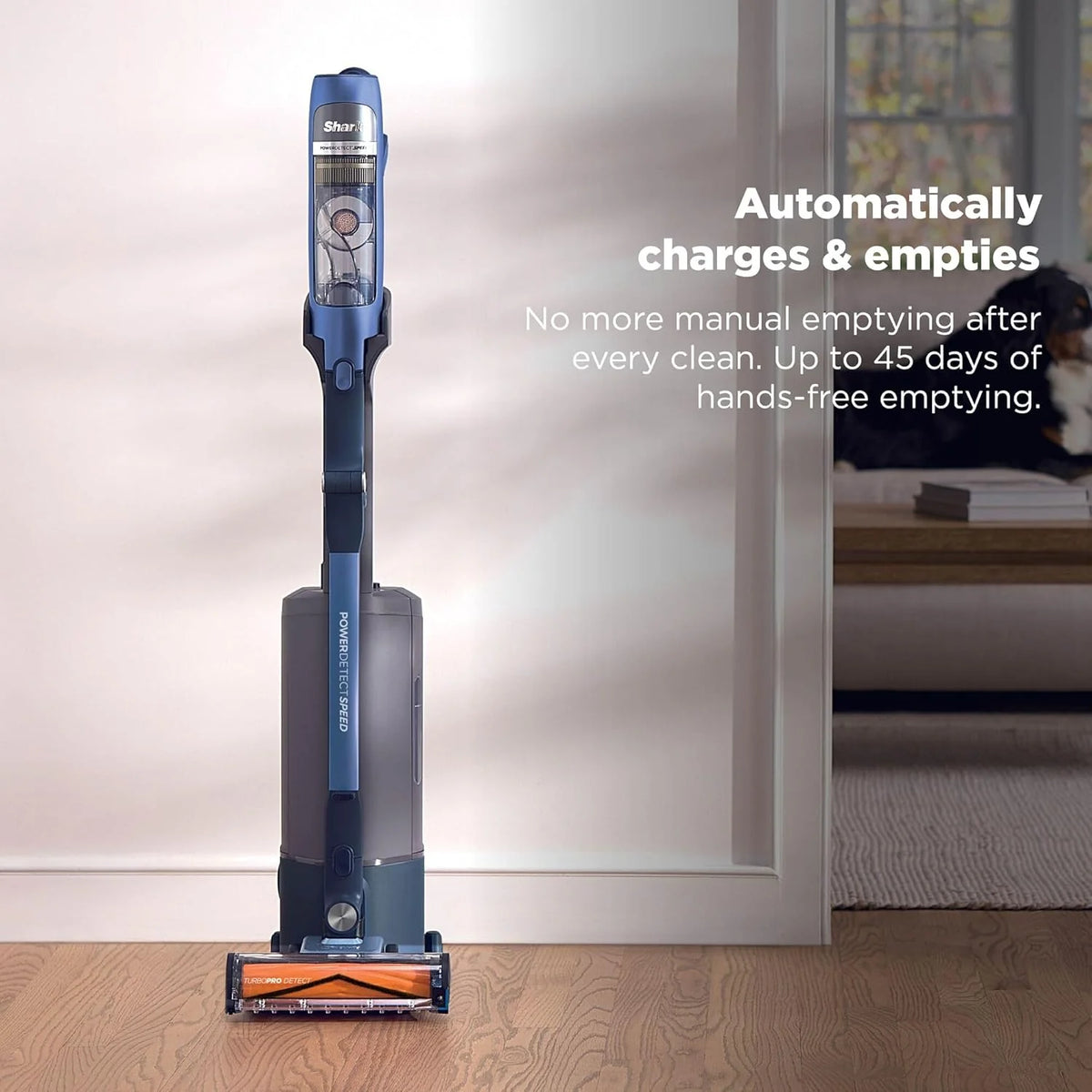 Shark PowerDetect Speed Clean & Empty Pet Vacuum in ultramarine standing on wooden floor near wall.