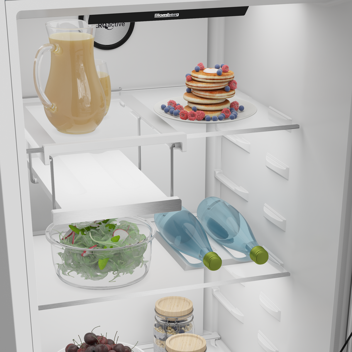 Interior of Blomberg tall larder fridge showing shelves with salad, bottles, jars, and a plate of pancakes with berries.