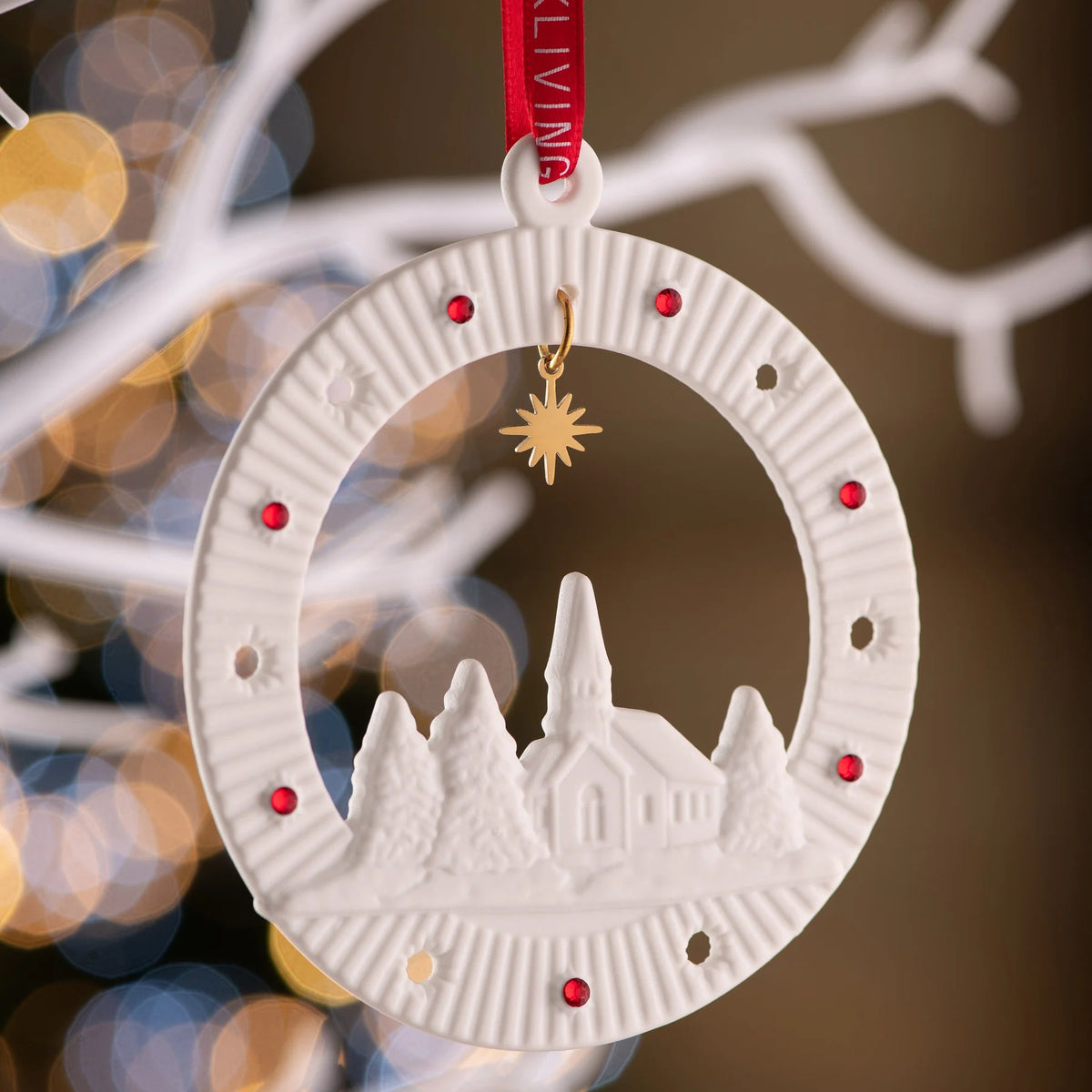 White Belleek Church Scene Ornament with red gems and a gold star charm hanging from a red ribbon