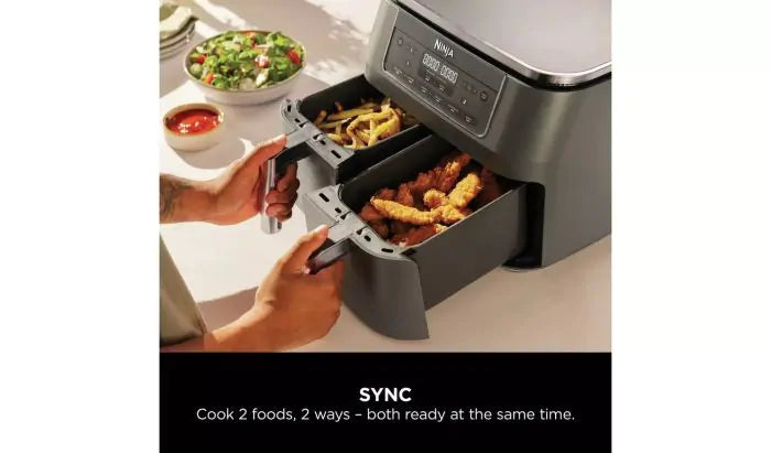 Ninja DZ300UK air fryer with dual baskets open, showing fries and chicken inside, on a kitchen counter.