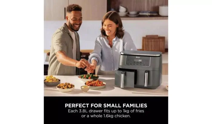 Ninja DZ300UK 6-in-1 Dual Zone Air Fryer 7.6L on kitchen counter with two people serving food nearby