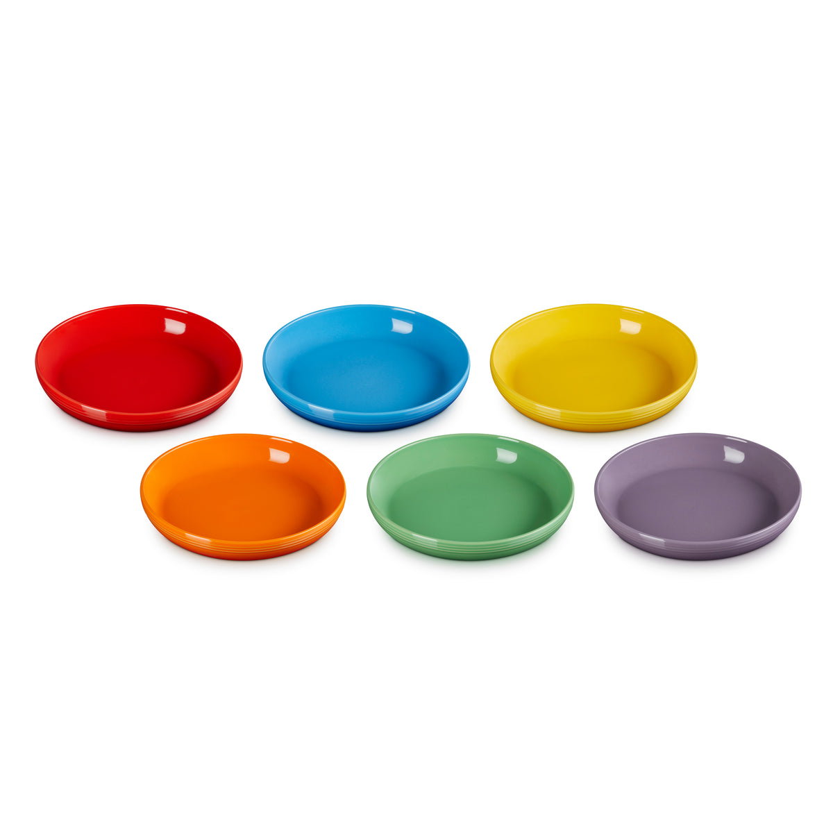 Six colorful Le Creuset coupe pasta bowls in red, blue, yellow, orange, green, and purple, stacked in pairs.