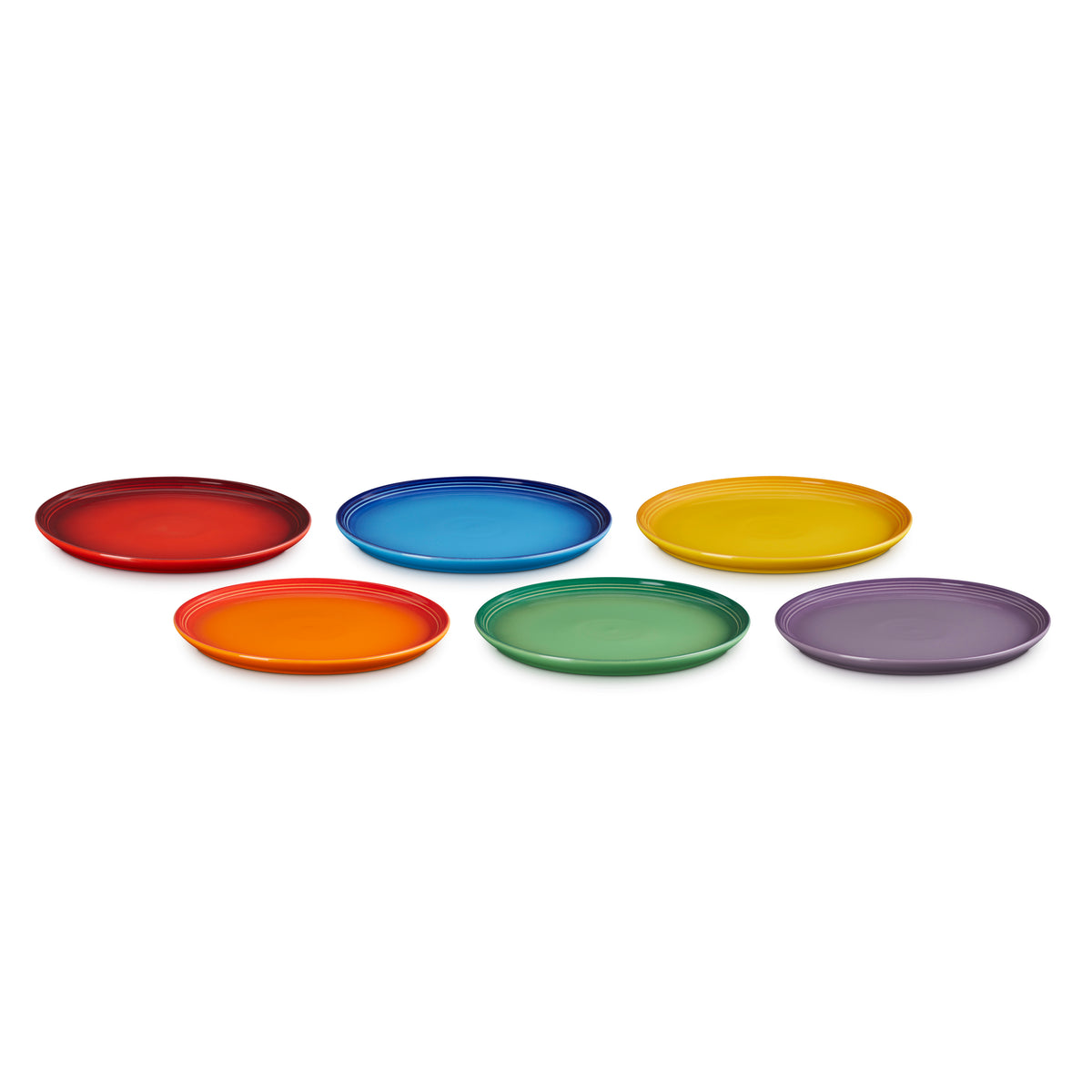 Six colorful Le Creuset coupe side plates in red, blue, yellow, orange, green, and purple on white background.
