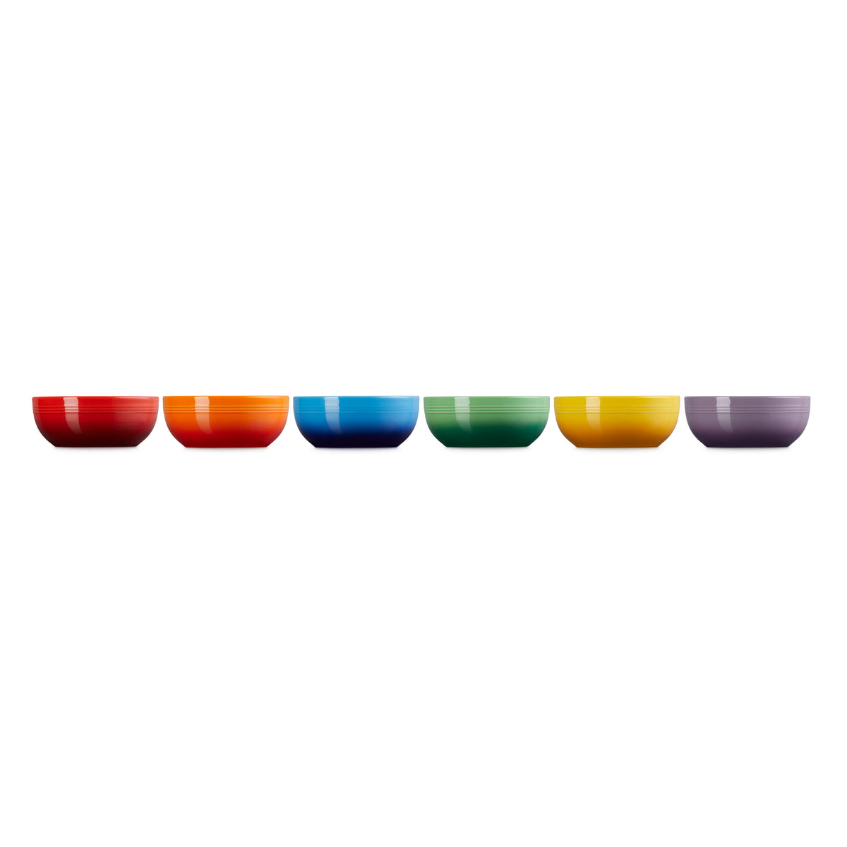 Six colorful Le Creuset coupe cereal bowls in red, orange, blue, green, yellow, and purple, side by side.