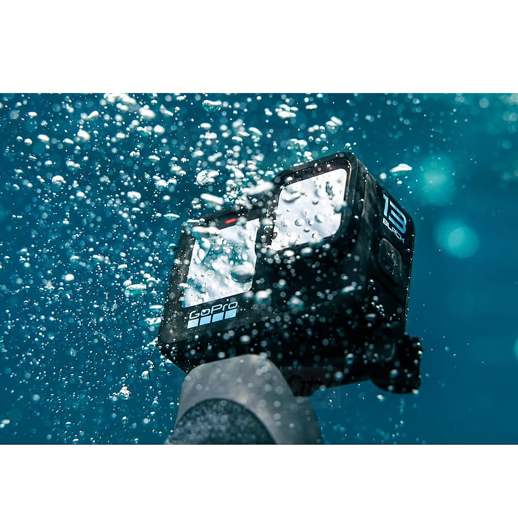 GoPro Hero 13 Black underwater with bubbles, held by a hand wearing a wetsuit sleeve.