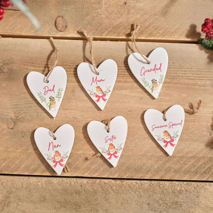 Six white ceramic heart hangers with robin illustrations and red text labels for family members on a wooden surface.
