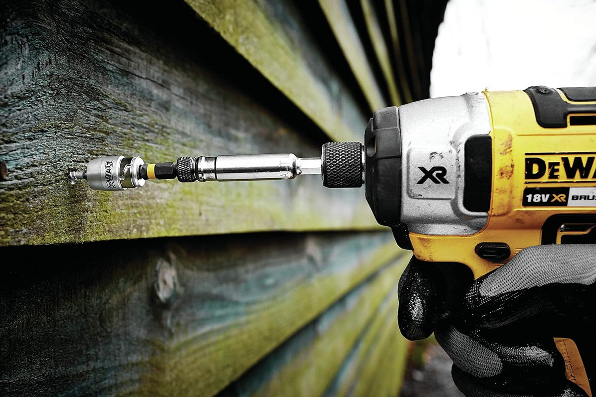DeWalt impact torsion bit and magnetic screwlock sleeve attached to a drill driving a screw into wood paneling.