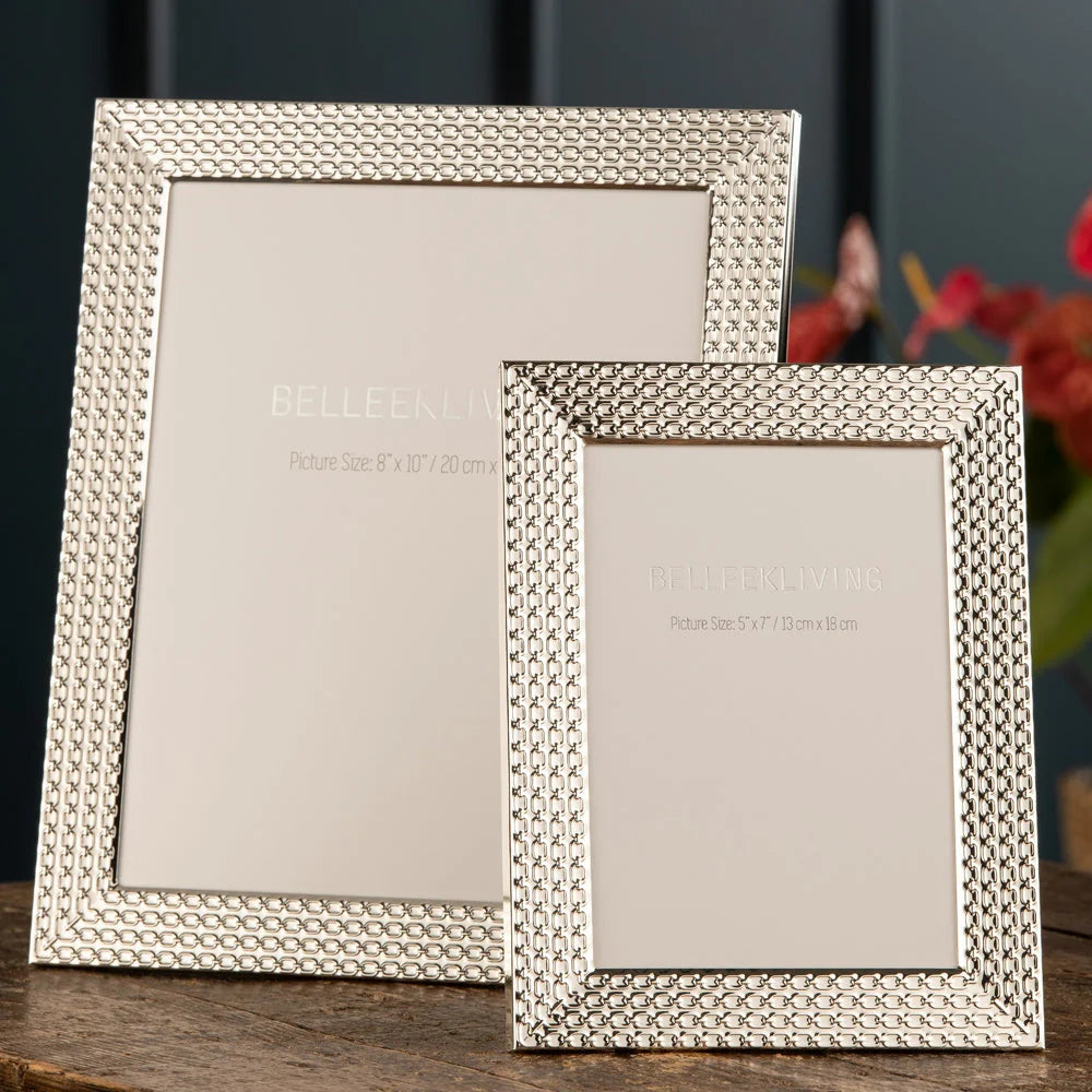 Two Belleek Living photo frames with textured silver borders, one 8x10 and one smaller 5x7, on a wooden surface.