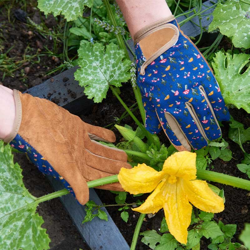 Mushrooms Smart Gardeners M8 gloves with leather palms and floral fabric backs worn while tending a yellow squash flower.