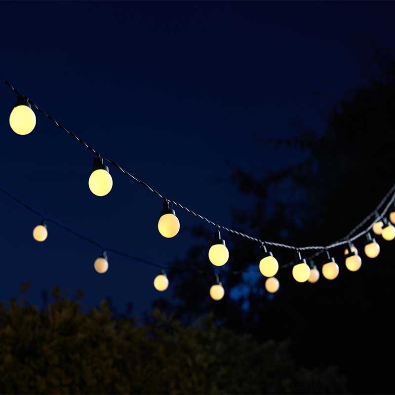 Warm white glowing Multi Power Festoon String Lights hanging outdoors against a dark night sky.