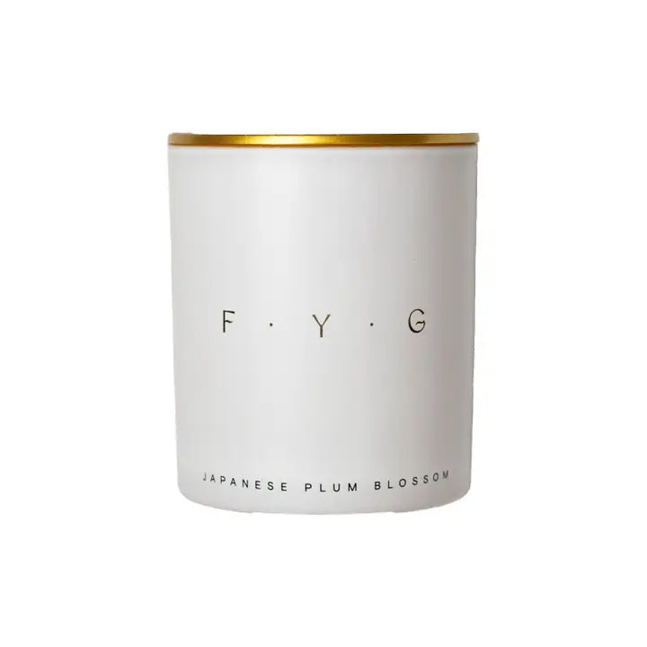 White candle jar with gold lid labeled F.Y.G Japanese Plum Blossom Candle