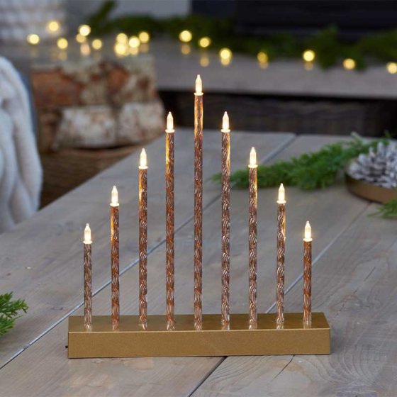 9 LED CandleBridge with gold base and twisted candle-like lights arranged in a stepped arch on a wooden table.
