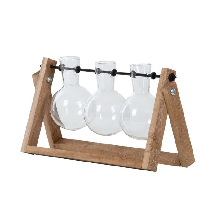 Set of three clear glass cutting vases suspended on a black rod within a wooden A-frame stand.