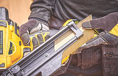Close-up of a person loading nails into a DeWalt DCN930N XR Framing Nailer 18V Bare Unit.