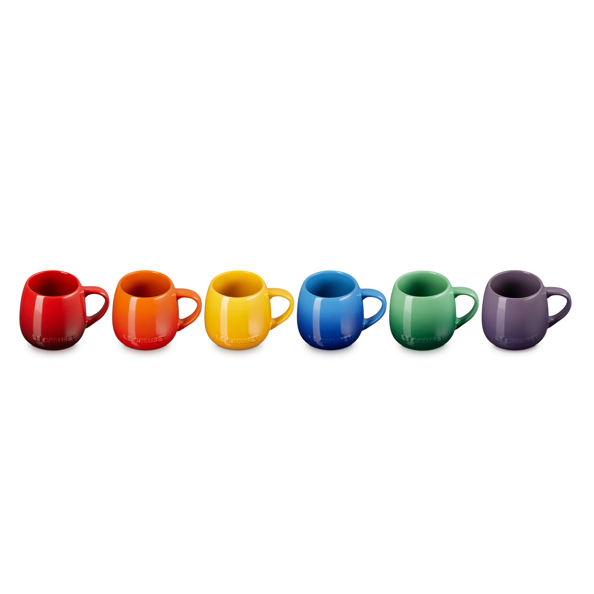 Le Creuset Rainbow set of six colorful coupe mugs in red, orange, yellow, blue, green, and purple, side by side.