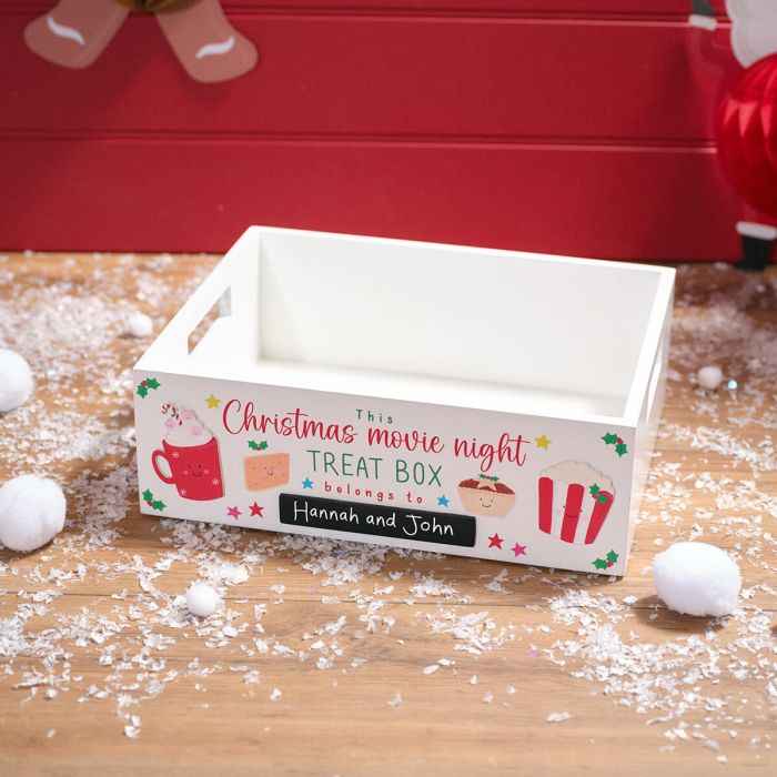 White wooden Christmas movie night treat box with festive illustrations and personalized names on front panel.