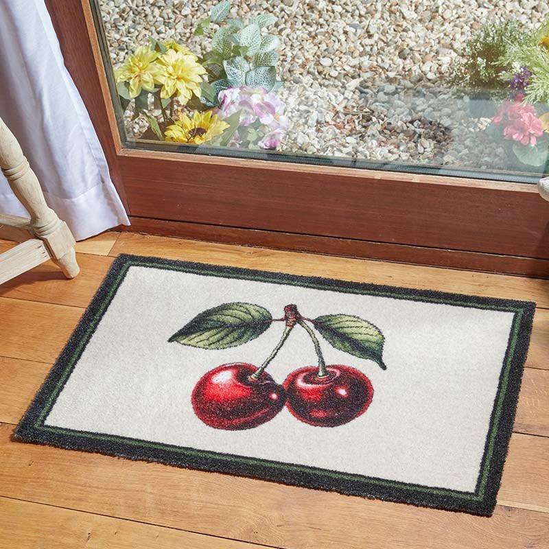 Cherries Ritzy Rug with two red cherries and green leaves on a cream background, placed on wooden floor.