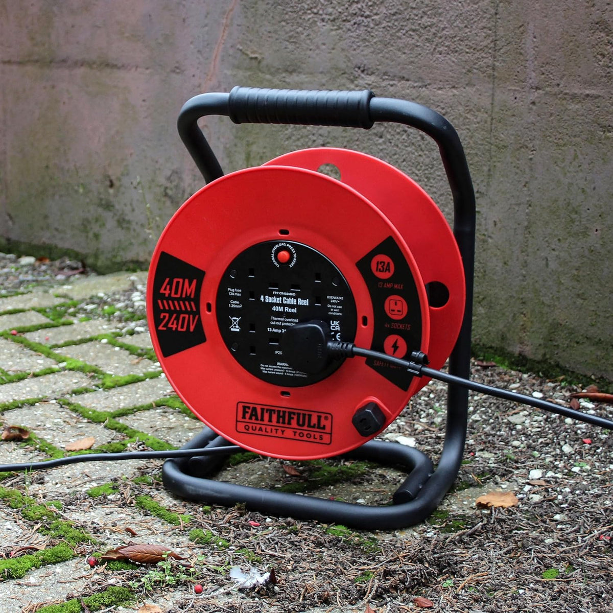 Faithfull 40m 13A heavy duty red cable reel with black frame and four sockets, plugged in outdoors.