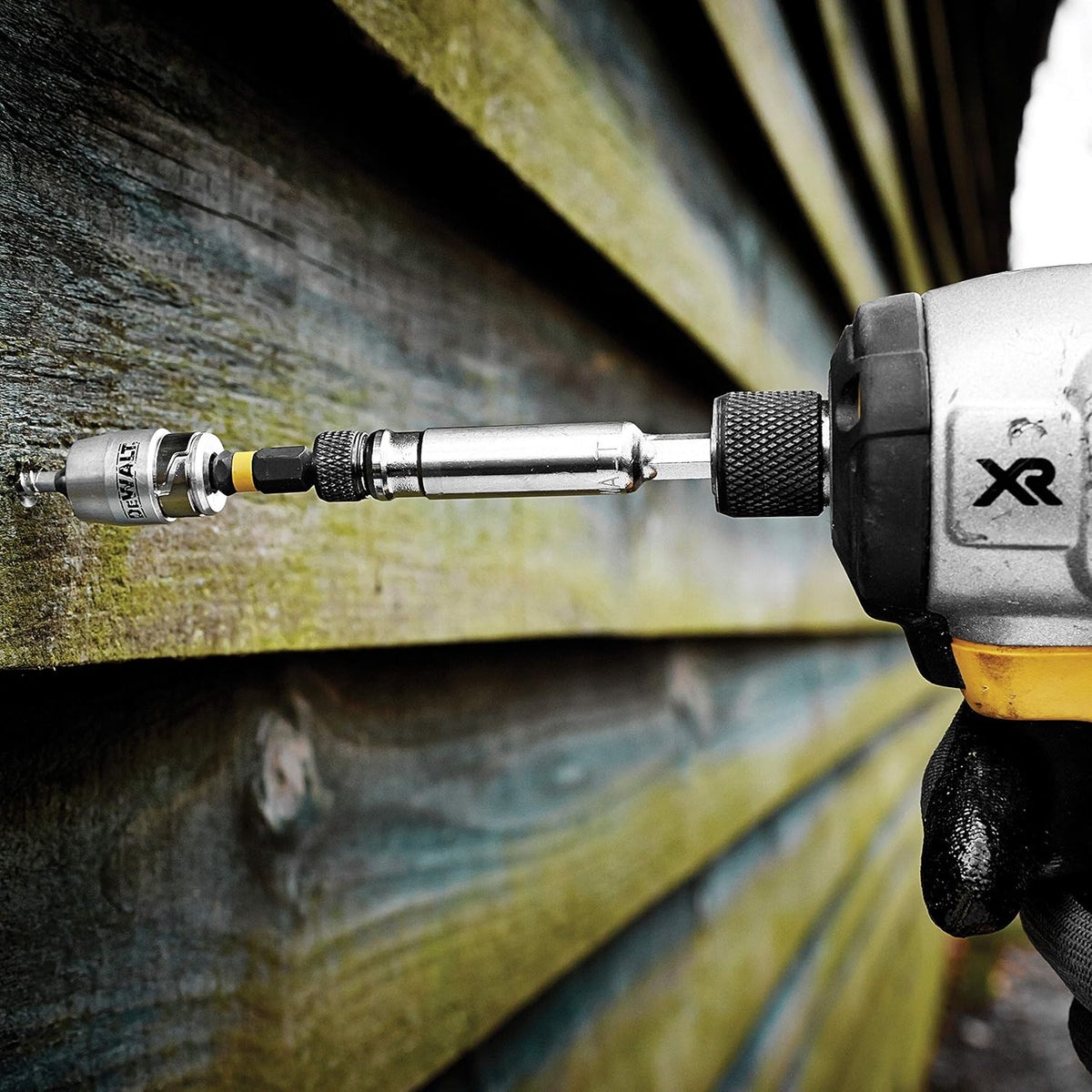 DeWalt impact torsion bit and magnetic screwlock sleeve attached to a drill driving a screw into wood.