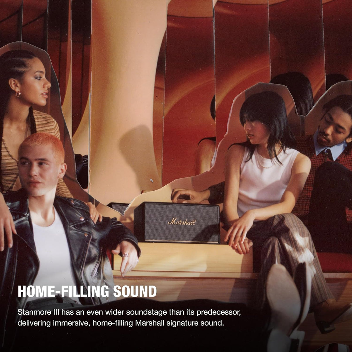 Marshall Stanmore III Bluetooth speaker in black on a wooden surface with four people sitting around it.