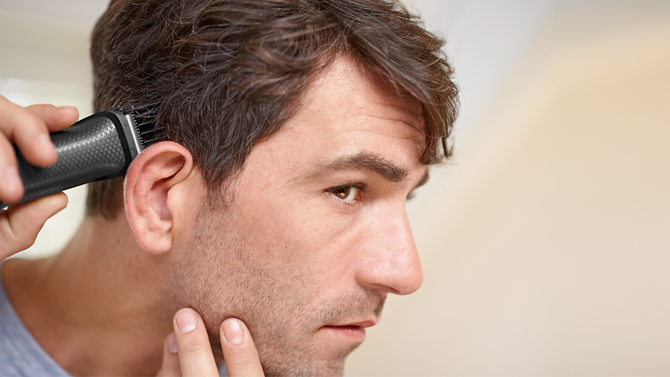 Man using Philips Multigroom Series 3000 trimmer to cut hair near ear
