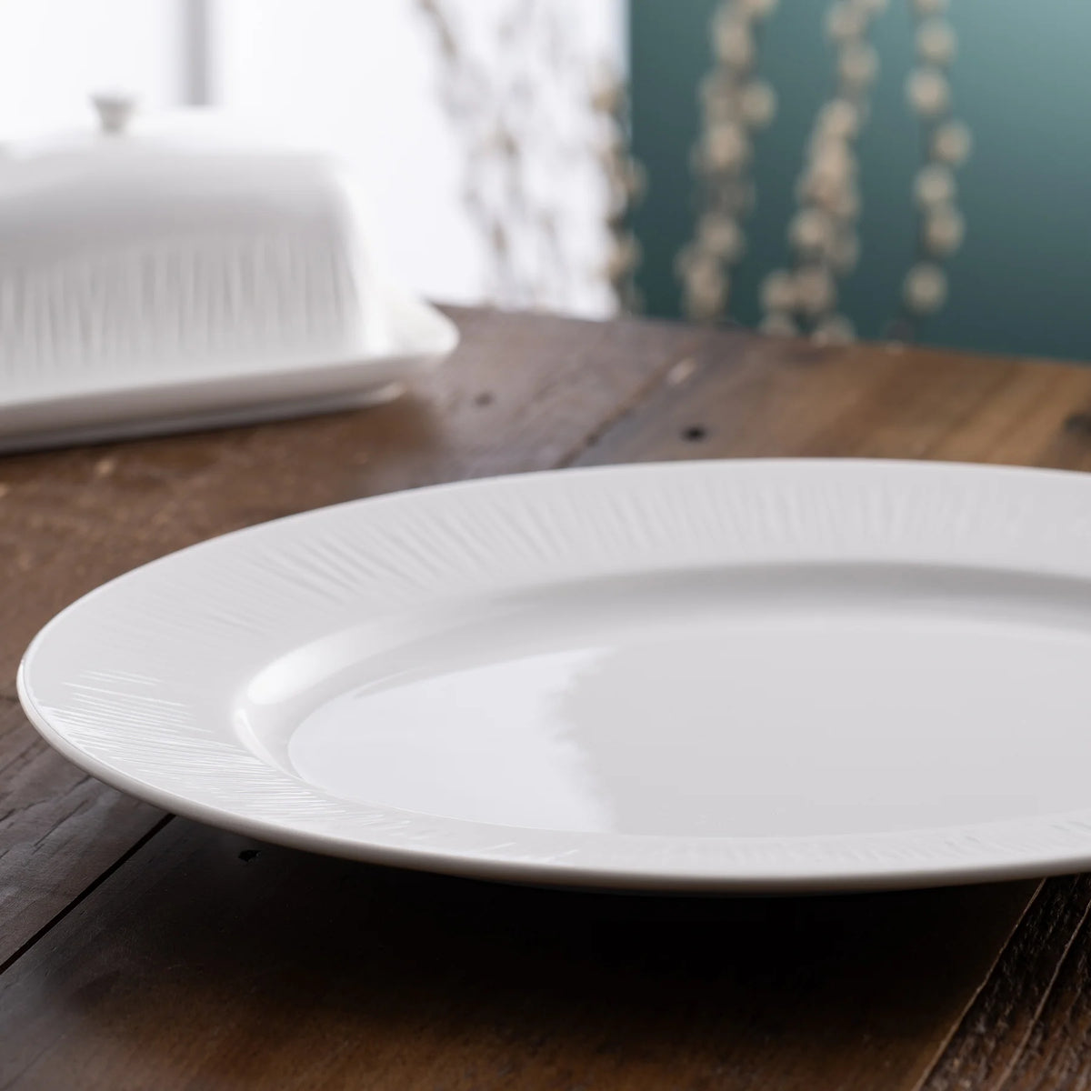 Erne Large Oval Platter with subtle textured rim on a wooden surface, angled view.
