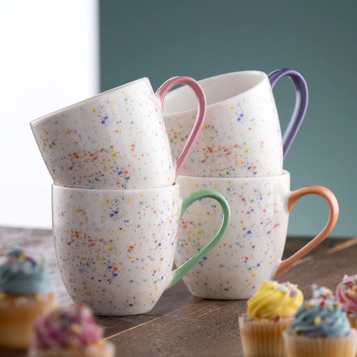 Stacked Confetti Mugs Set of 4 with multicolored speckles and pastel-colored handles on a wooden surface.