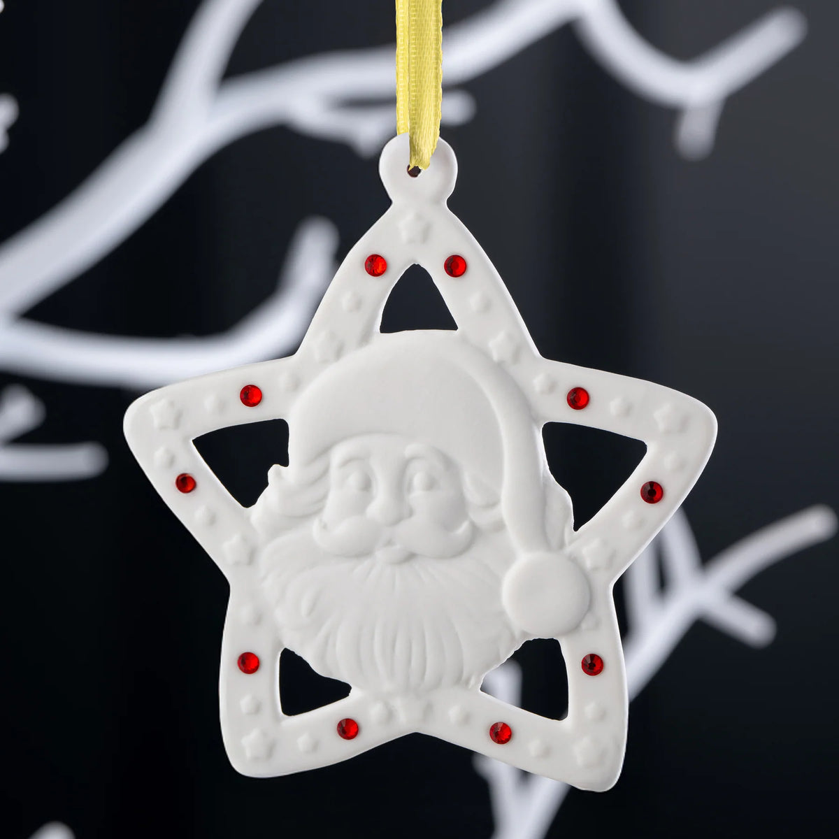 White star-shaped Belleek ornament with Santa face and red gem accents hanging on yellow ribbon
