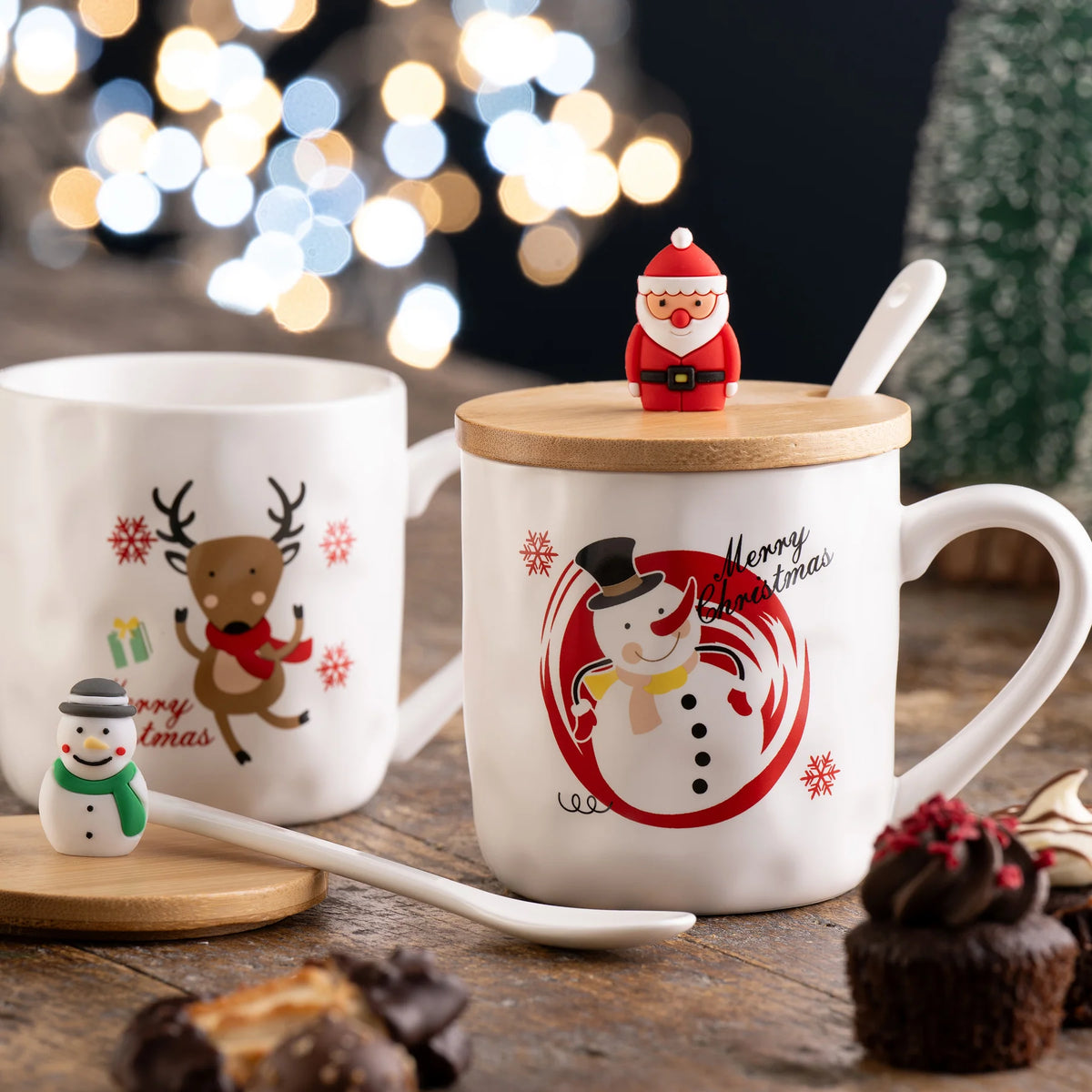 White mug with a snowman design, wooden lid topped with a Santa figure, and a white spoon on a wooden table.