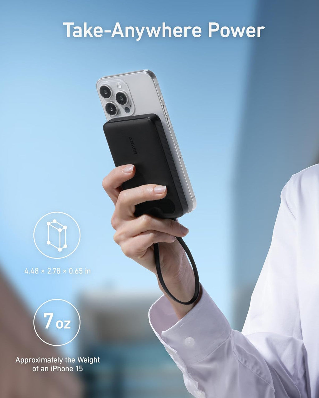 Hand holding an iPhone 15 with an Anker 10K PD Power Bank attached via a built-in cable against a blue sky.