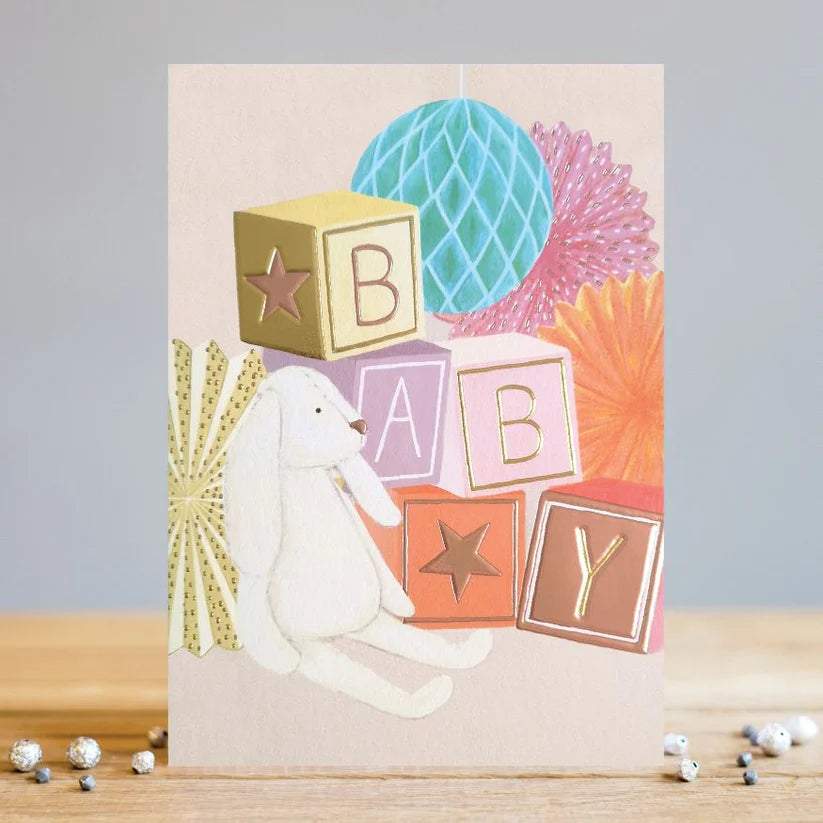 LT New Baby card with a white plush bunny and colorful blocks spelling "BABY" on textured card.