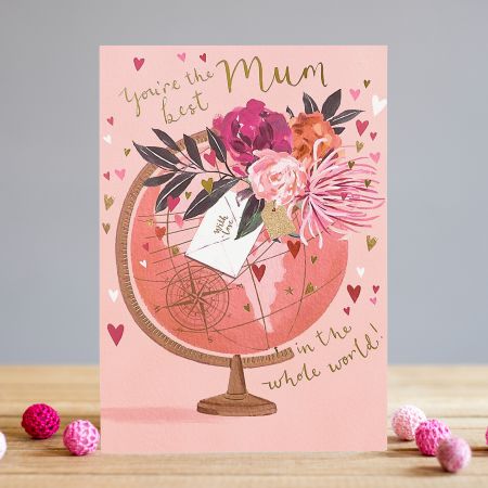 Best Mum World Card with pink globe, flowers, hearts, and gold script on textured cardstock, standing on wooden surface.