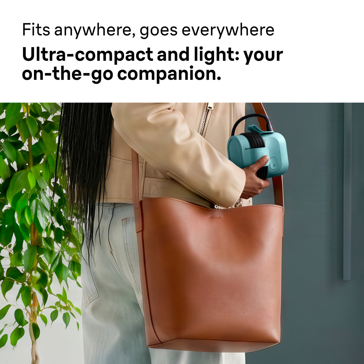 Person holding a compact green Braun Carestyle Mini Travel Garment Steamer with cord wrapped around it.