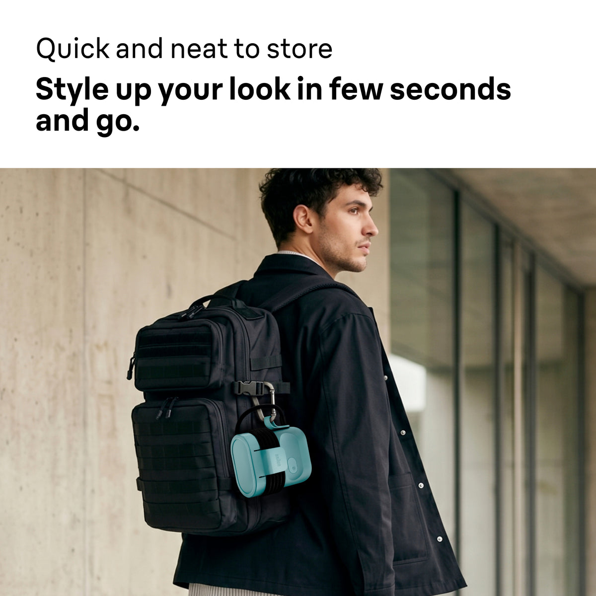 Braun Carestyle Mini Travel Garment Steamer in green clipped to a black backpack worn by a man in a black jacket