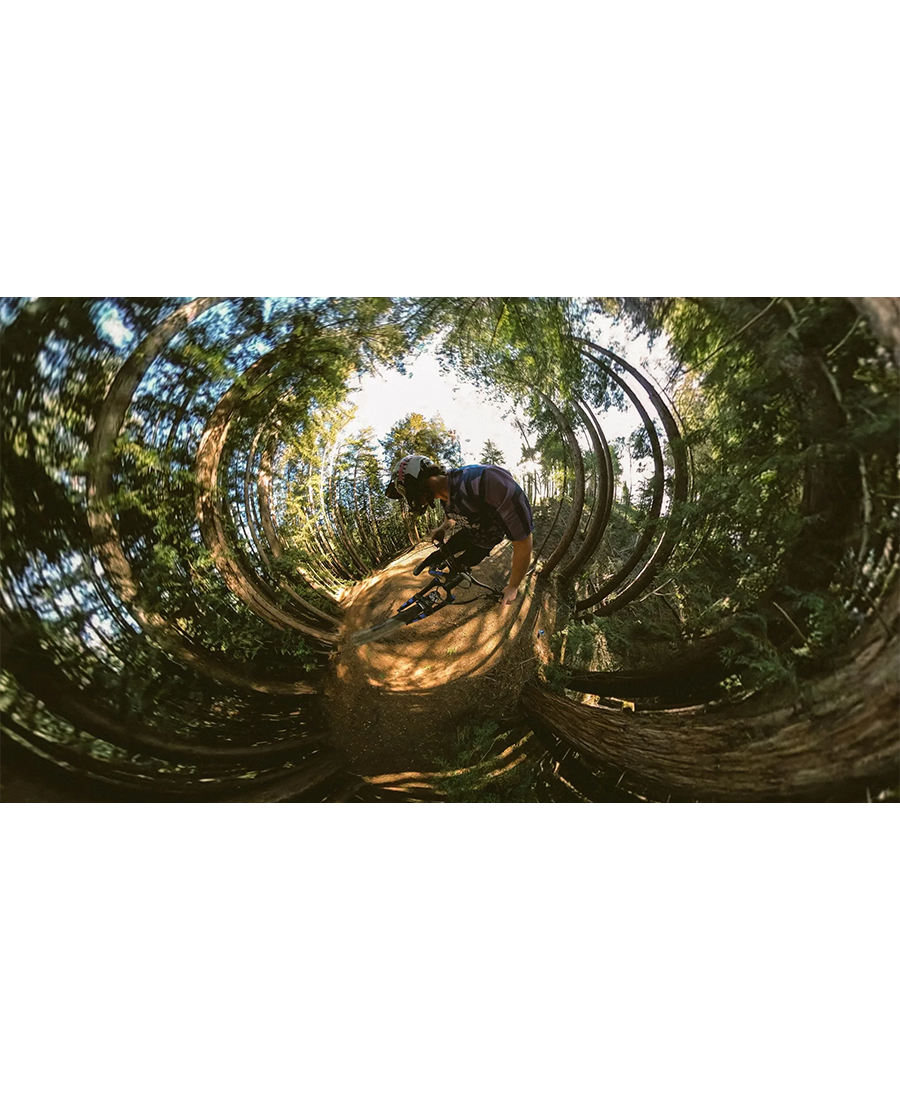 360-degree fisheye view of a cyclist wearing a helmet riding a bike on a forest trail captured by GoPro Hero Max.