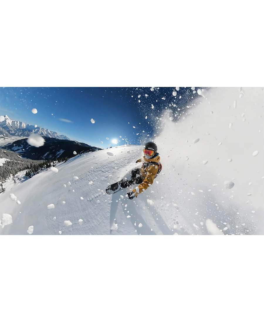 Snowboarder captured in action on a snowy mountain slope with snow flying around, shot with GoPro Hero Max 360 camera