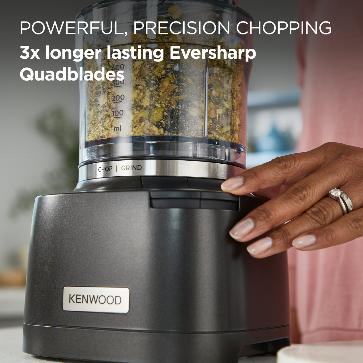 Kenwood Autograph Duo Prep 2 in 1 chopper/grinder with hand pressing button and chopped ingredients inside bowl