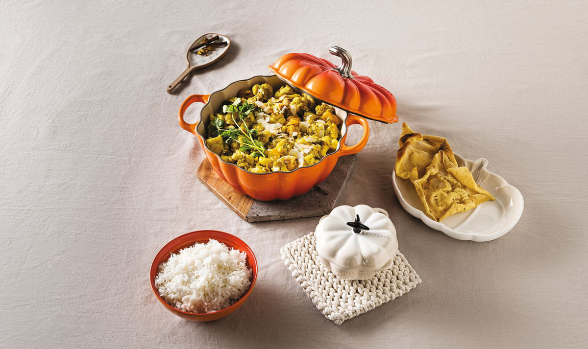 Le Creuset Halloween Pumpkin Butterdish Volcanic in orange with lid off, filled with cooked vegetables on table.