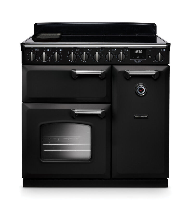 Rangemaster Classic Deluxe 90cm black induction rangecooker with multiple ovens, chrome handles, and control dials.