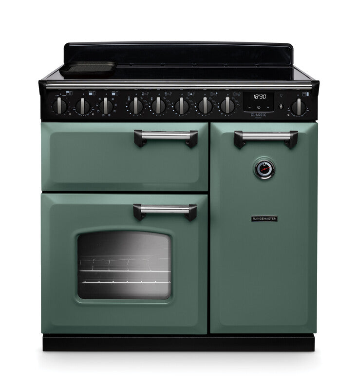 Rangemaster Classic Deluxe 90cm chrome induction rangecooker in green with multiple control knobs and oven window.
