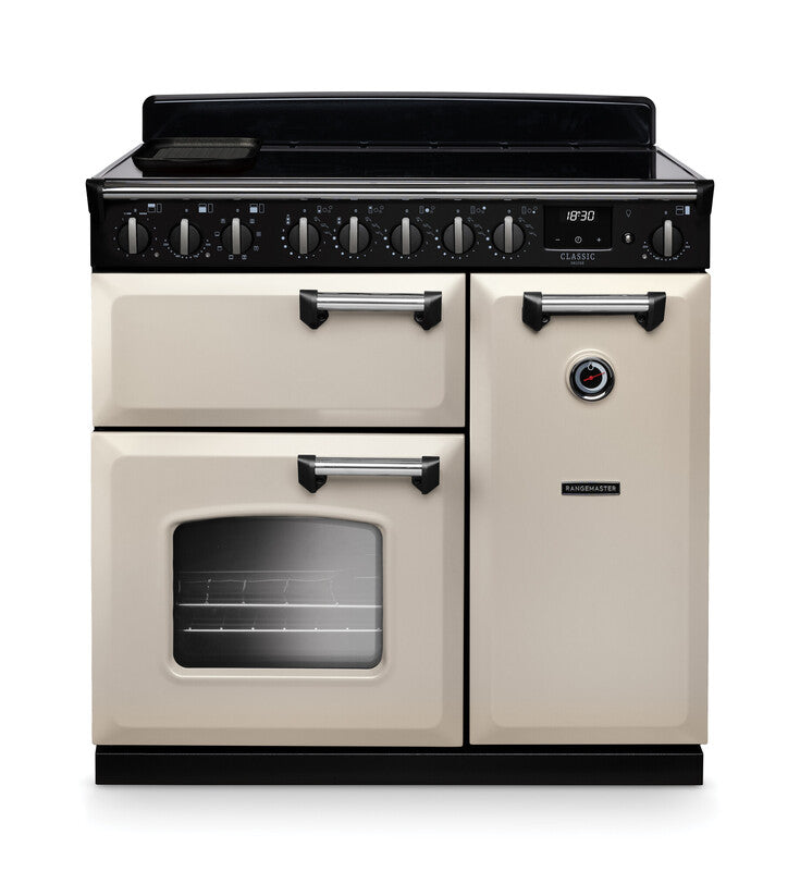 Rangemaster Classic Deluxe 90cm cream and chrome induction rangecooker with multiple control knobs and oven window.