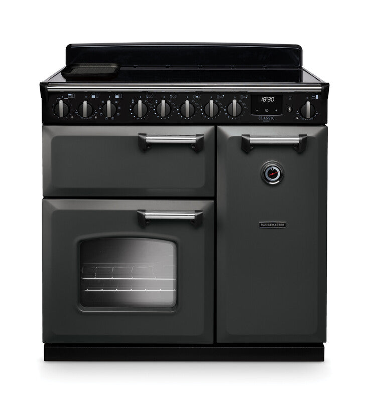 Rangemaster Classic Deluxe 90cm chrome induction rangecooker with multiple control knobs and oven doors, black finish.